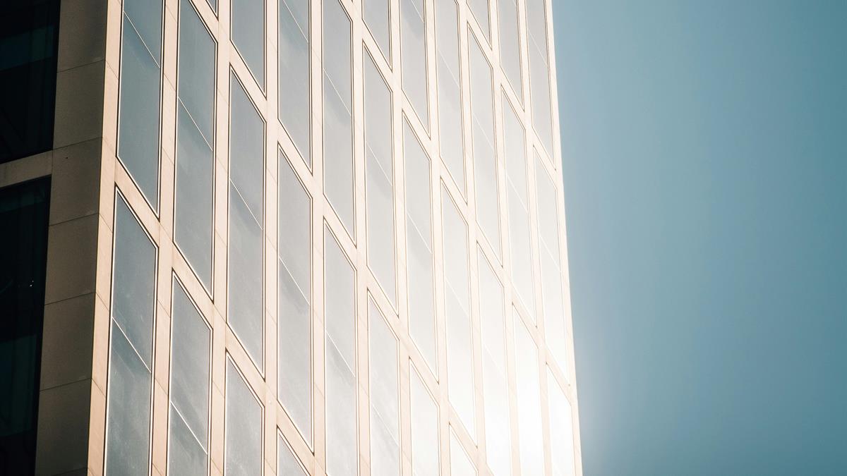 Fachada de prédio com vidros refletindo o sol, aplicação de película comercial
