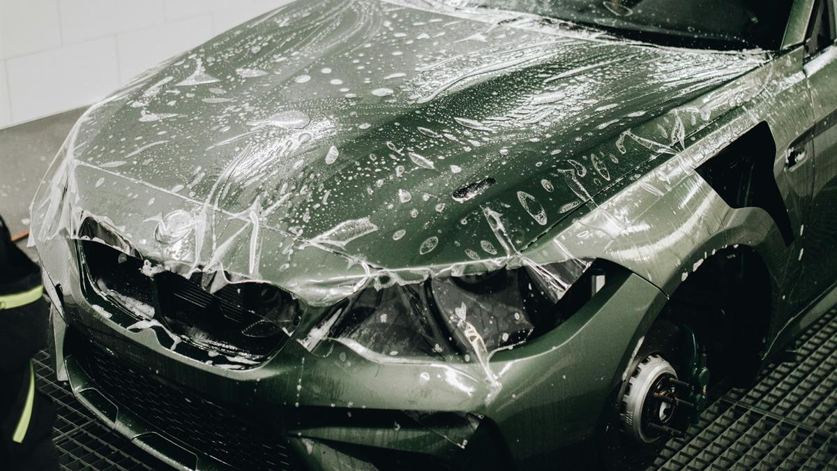 Aplicação de PPF, película transparente de proteção de pintura, no capô de um carro
